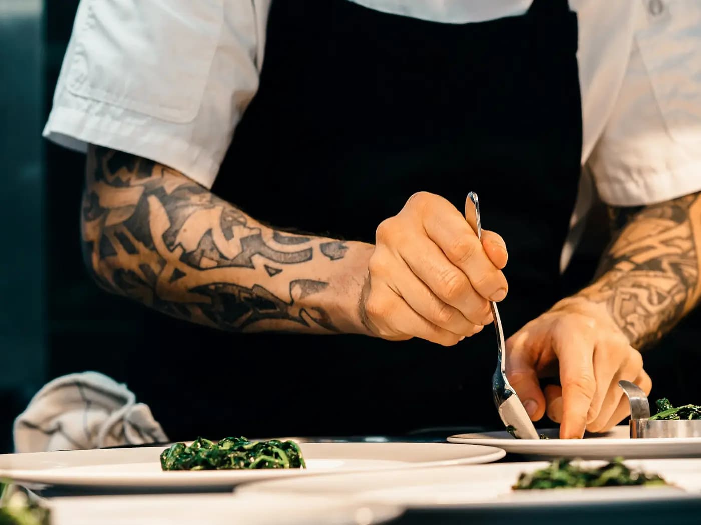 A chef plating dishes in a kitchen.